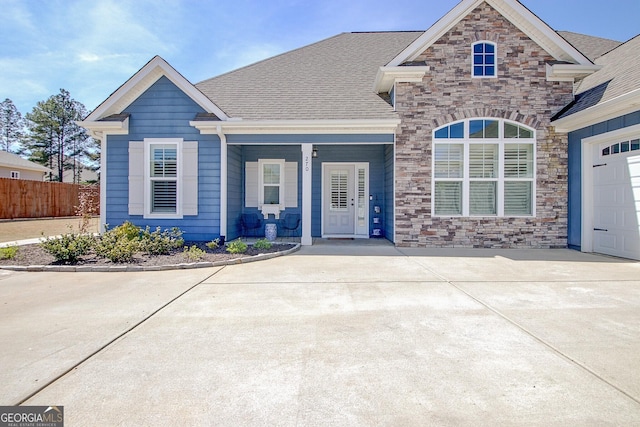view of front facade featuring fence, a porch, and stone siding