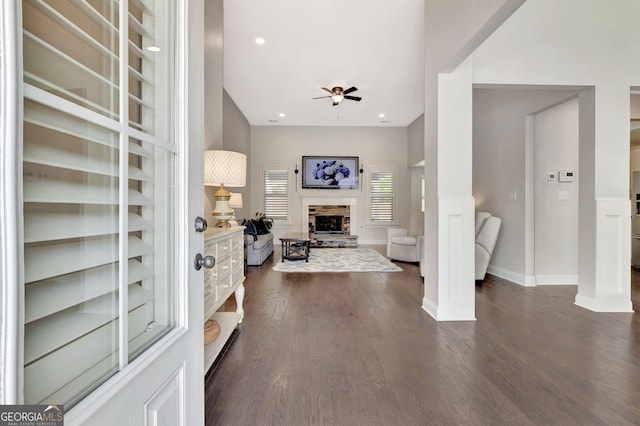 foyer entrance with ceiling fan, dark wood finished floors, baseboards, a fireplace with raised hearth, and recessed lighting