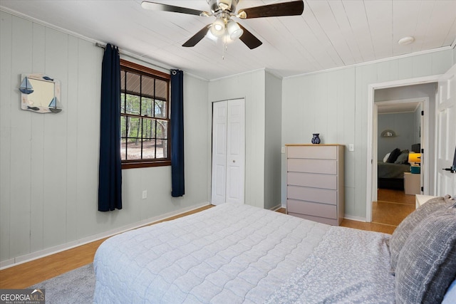 bedroom featuring a closet, light wood finished floors, ornamental molding, ceiling fan, and an AC wall unit