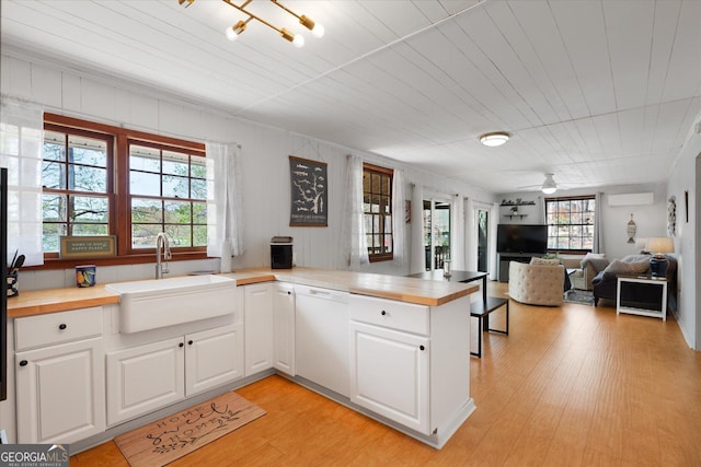kitchen featuring a sink, butcher block countertops, white dishwasher, stainless steel microwave, and white cabinets