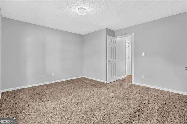 carpeted empty room featuring baseboards and a textured ceiling