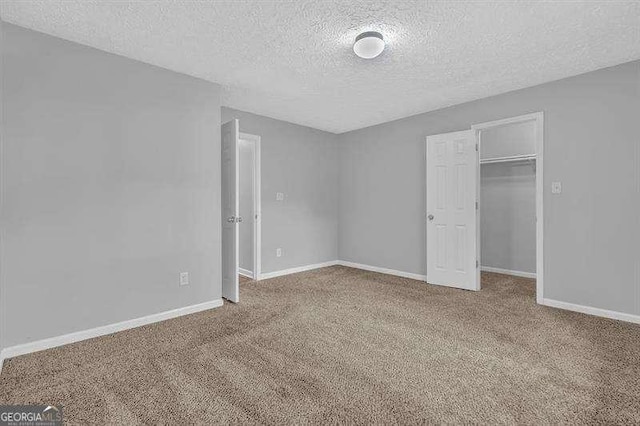 unfurnished bedroom featuring carpet floors, a walk in closet, baseboards, and a closet