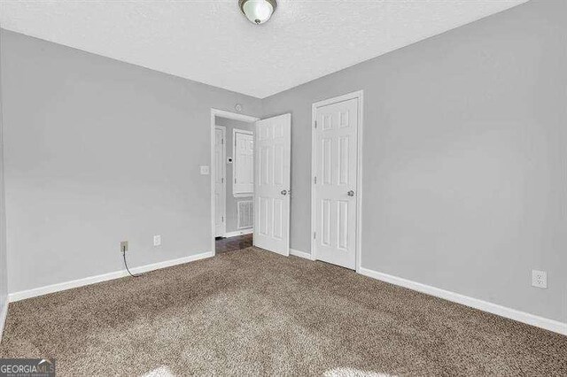 unfurnished bedroom with baseboards, carpet flooring, a textured ceiling, and a closet