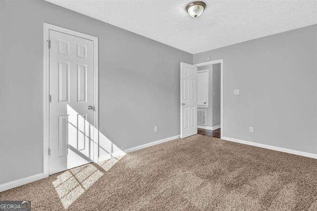 unfurnished room featuring baseboards, carpet flooring, and a textured ceiling