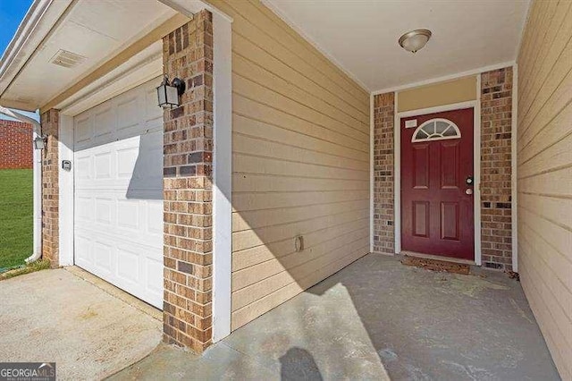 doorway to property with brick siding and a garage