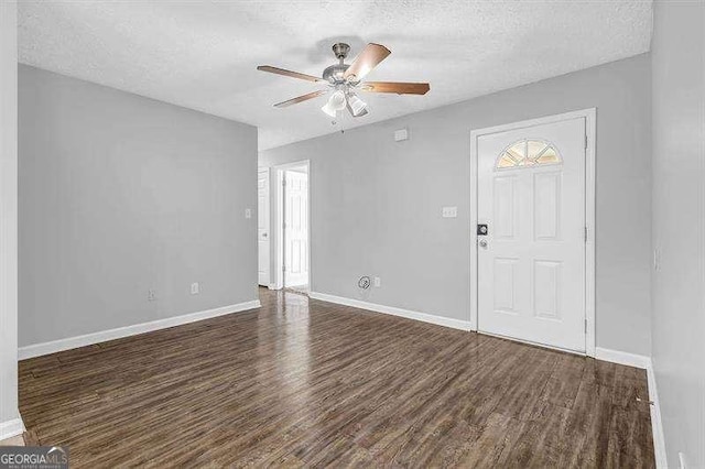 interior space featuring a textured ceiling, baseboards, ceiling fan, and dark wood finished floors
