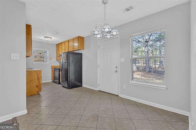 kitchen with baseboards, visible vents, a chandelier, and freestanding refrigerator