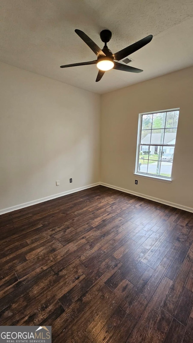 unfurnished room featuring a ceiling fan, a textured ceiling, baseboards, and dark wood finished floors