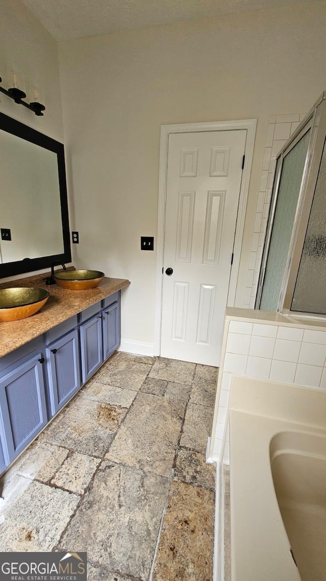 bathroom with a sink, stone tile flooring, and a bathing tub