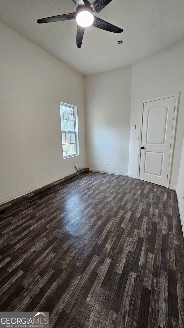 unfurnished room with baseboards, a textured ceiling, dark wood-type flooring, and a ceiling fan