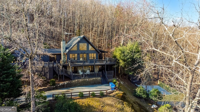 back of property with a chimney, fence, stairway, and a view of trees