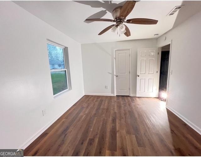 empty room featuring baseboards, visible vents, wood finished floors, and ceiling fan