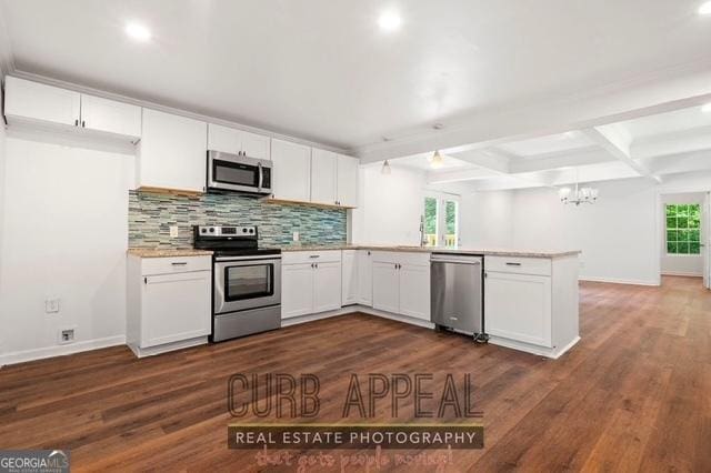 kitchen featuring beam ceiling, tasteful backsplash, a peninsula, and appliances with stainless steel finishes