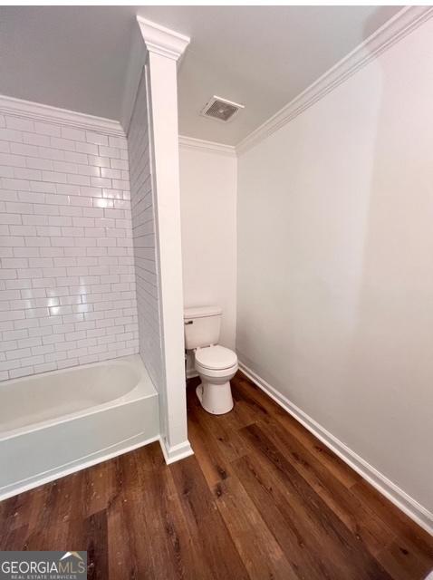 bathroom featuring visible vents, baseboards, ornamental molding, toilet, and wood finished floors