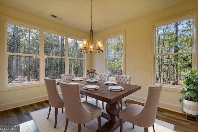 dining area featuring visible vents, baseboards, an inviting chandelier, and wood finished floors