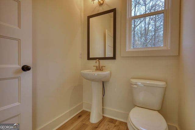 half bath featuring baseboards, toilet, and wood finished floors