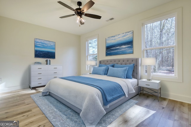 bedroom featuring visible vents, multiple windows, baseboards, and light wood-style flooring