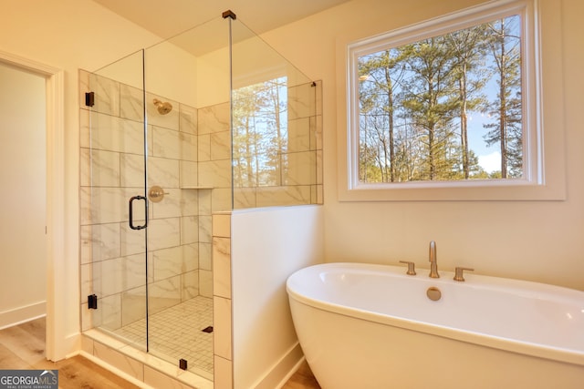 bathroom featuring a wealth of natural light, a freestanding bath, a stall shower, and baseboards