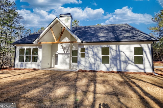 back of house featuring a chimney and a shingled roof