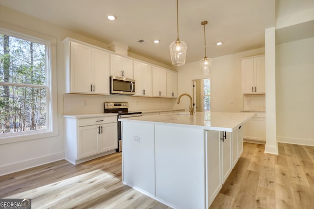 kitchen with light countertops, backsplash, visible vents, appliances with stainless steel finishes, and a sink