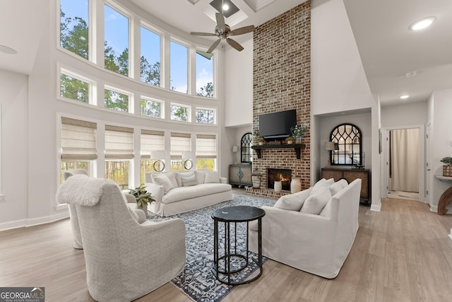 6635 Canyon Cv, Cumming, GA 30028 - living area featuring light wood-type flooring, baseboards, a towering ceiling, a ceiling fan, and a fireplace