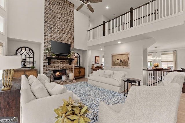 6635 Canyon Cv, Cumming, GA 30028 - living room featuring wood finished floors, ceiling fan with notable chandelier, a high ceiling, a brick fireplace, and recessed lighting