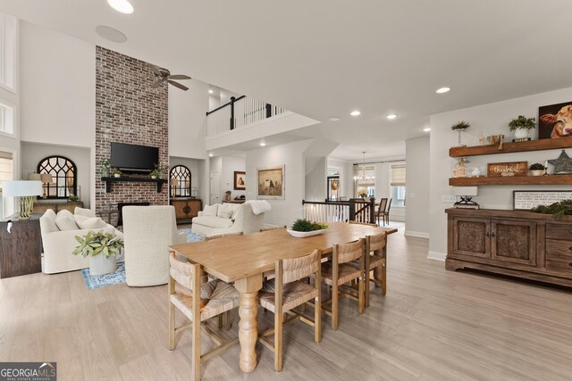 6635 Canyon Cv, Cumming, GA 30028 - dining area featuring light wood finished floors, a towering ceiling, recessed lighting, a ceiling fan, and a brick fireplace