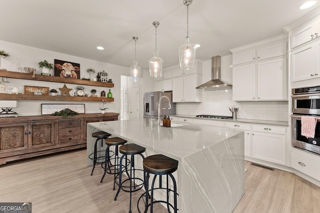 6635 Canyon Cv, Cumming, GA 30028 - kitchen with wall chimney exhaust hood, light wood finished floors, backsplash, open shelves, and appliances with stainless steel finishes