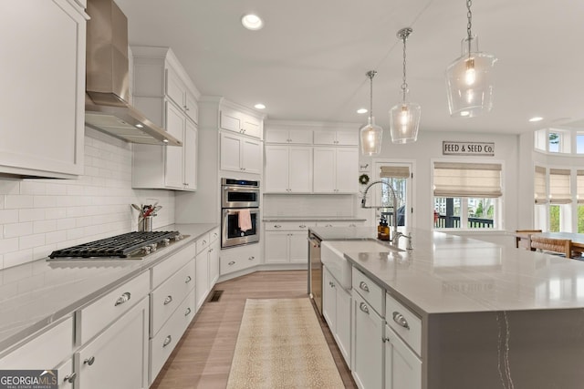6635 Canyon Cv, Cumming, GA 30028 - kitchen featuring wall chimney range hood, a sink, a large island with sink, appliances with stainless steel finishes, and recessed lighting