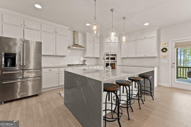 6635 Canyon Cv, Cumming, GA 30028 - kitchen featuring wall chimney exhaust hood, light wood-type flooring, decorative backsplash, light countertops, and appliances with stainless steel finishes