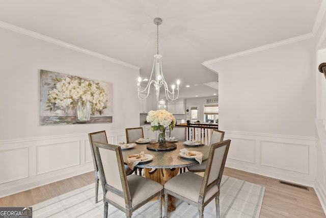 6635 Canyon Cv, Cumming, GA 30028 - dining space featuring an inviting chandelier, ornamental molding, visible vents, and light wood-type flooring