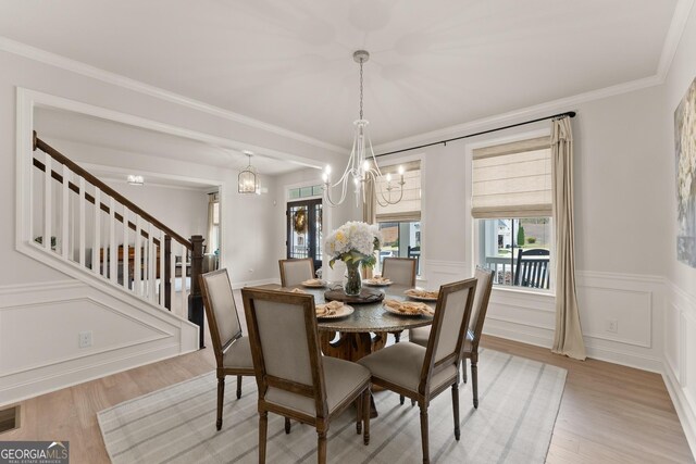 6635 Canyon Cv, Cumming, GA 30028 - dining space featuring light wood-style flooring, wainscoting, visible vents, a notable chandelier, and stairs