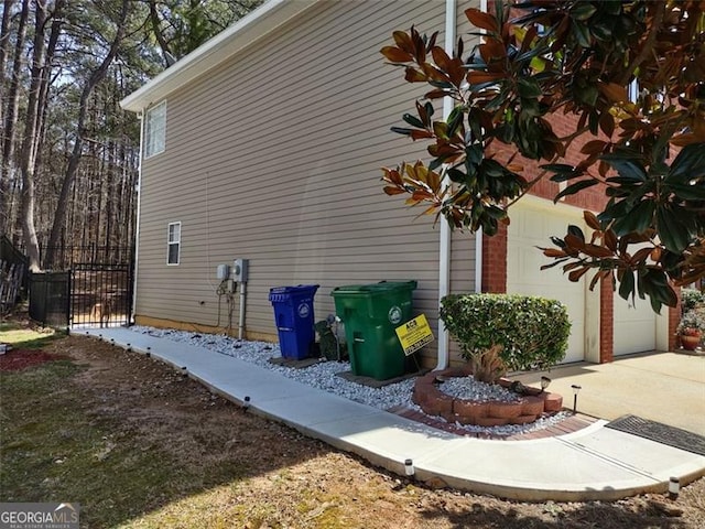 view of home's exterior with driveway, a garage, and fence