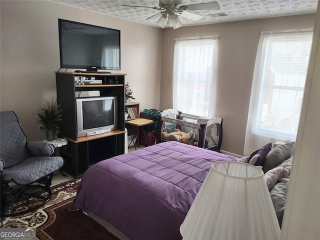 bedroom featuring a textured ceiling, ceiling fan, and visible vents