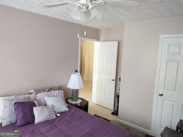 bedroom featuring a textured ceiling, a ceiling fan, and light carpet
