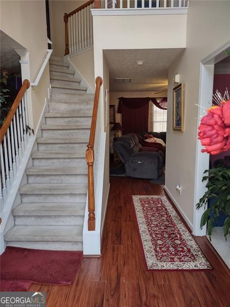 stairs with baseboards, visible vents, and wood finished floors