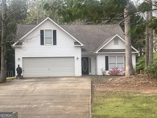 traditional home with roof with shingles, an attached garage, and driveway