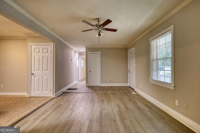 unfurnished living room with visible vents, crown molding, baseboards, ceiling fan, and wood finished floors