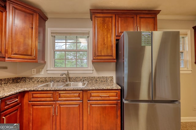 kitchen featuring ornamental molding, a sink, light stone countertops, and freestanding refrigerator