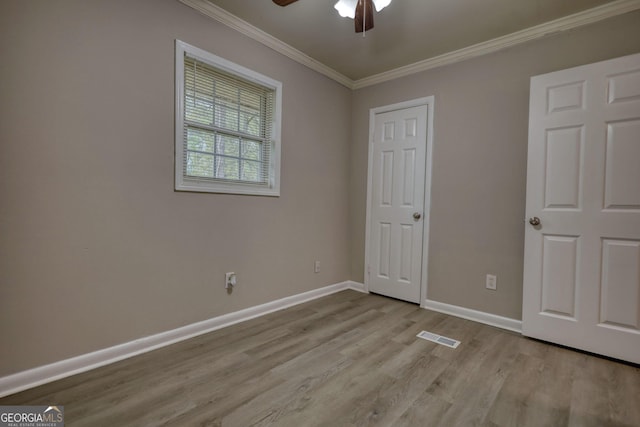 unfurnished bedroom featuring crown molding, wood finished floors, baseboards, visible vents, and ceiling fan