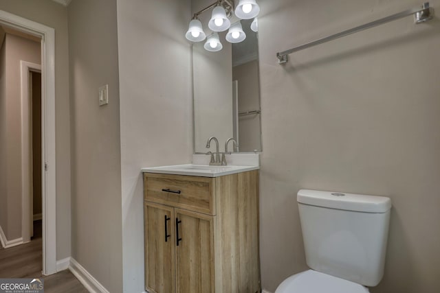 bathroom with toilet, vanity, baseboards, and wood finished floors