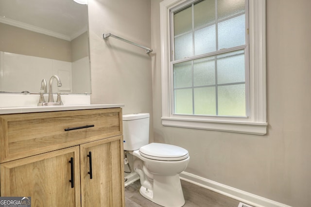 bathroom with crown molding, toilet, vanity, wood finished floors, and baseboards