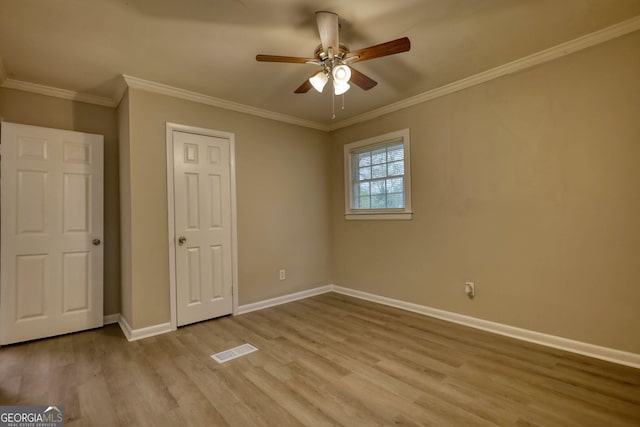 unfurnished bedroom with light wood-type flooring, ornamental molding, baseboards, visible vents, and ceiling fan