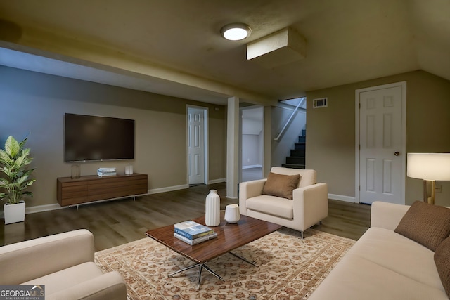 living room featuring baseboards, visible vents, wood finished floors, and stairway