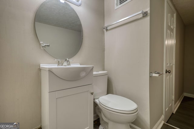 bathroom featuring baseboards, visible vents, toilet, and vanity