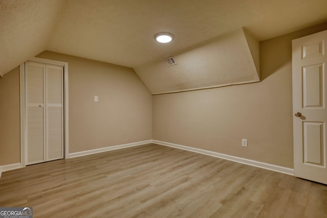 bonus room featuring baseboards, lofted ceiling, visible vents, and light wood-style floors