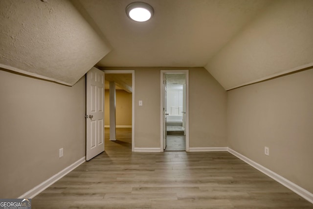 additional living space with baseboards, lofted ceiling, and wood finished floors