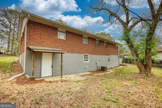 rear view of property with cooling unit and brick siding