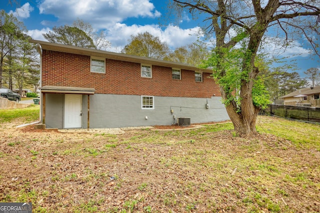 back of property featuring central AC unit, fence, and brick siding