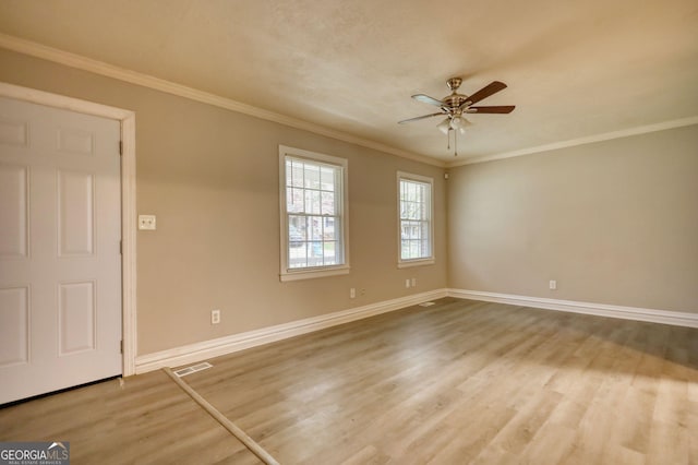 spare room with crown molding, baseboards, visible vents, a ceiling fan, and wood finished floors